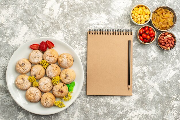 Bovenaanzicht lekkere zoete koekjes met rozijnen op witte achtergrond candy cookie biscuit zoete thee suiker