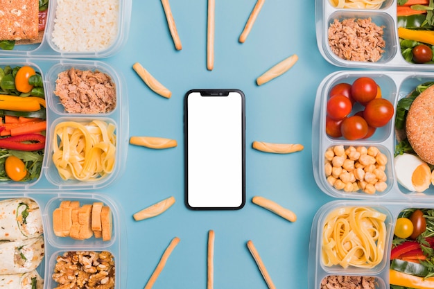 Bovenaanzicht lunchboxen met lege telefoon en breadsticks