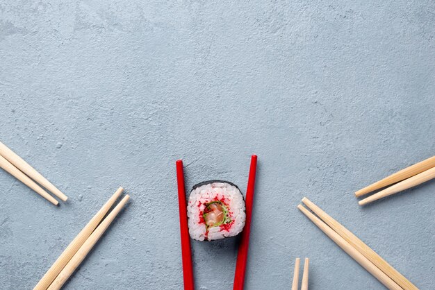 Bovenaanzicht maki sushi roll en eetstokjes met kopie ruimte