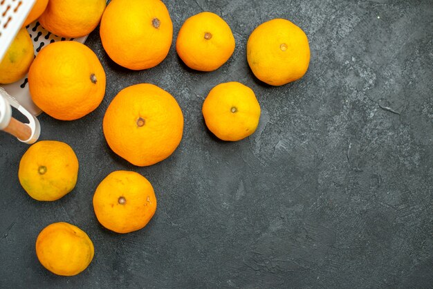 Bovenaanzicht mandarijnen en sinaasappels verspreid uit plastic mand op donkere ondergrond