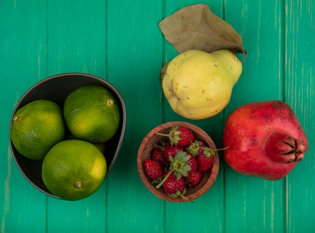 Bovenaanzicht mandarijnen in een kom en granaatappel peer en aardbeien