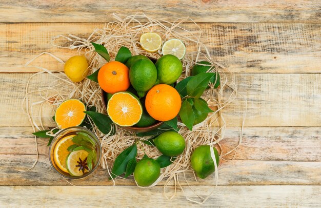 Bovenaanzicht mandarijnen in pot met kruidenthee op houten bord