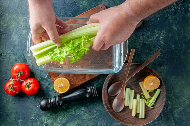 Bovenaanzicht mannelijke kok selderij uit plaat met water op een donkere tafel salade dieet maaltijd foto voedsel gezondheid kleur te nemen