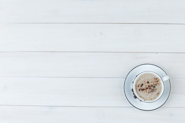 Bovenaanzicht melkachtige koffie in beker op houten achtergrond. horizontaal