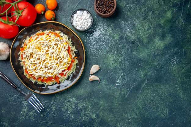 bovenaanzicht mimosa salade binnen plaat met kruiden en rode tomaten op donkerblauwe achtergrond