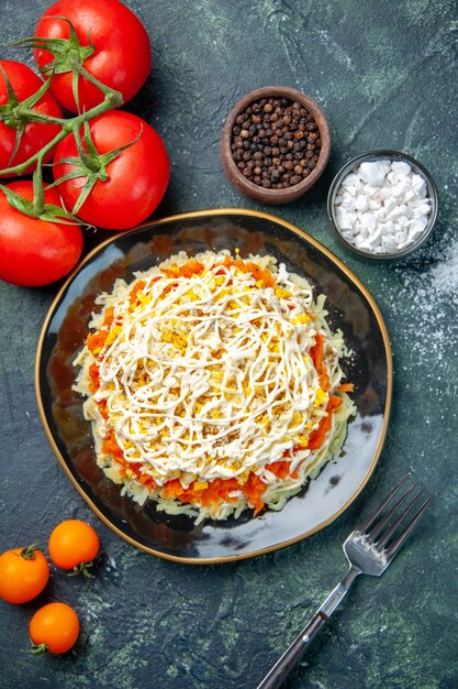 bovenaanzicht mimosa salade binnen plaat met kruiden en tomaten op donkerblauwe achtergrond