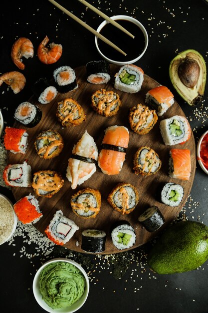 Bovenaanzicht mix broodjes op een standaard met saus sojasaus wasabi gember avocado en sesamzaadjes