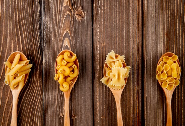 Bovenaanzicht mix pasta farfalle penne elleboog macaroni en farfalle tonde met kopie ruimte op houten achtergrondkleur