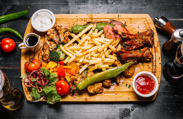 Bovenaanzicht mix van vlees snacks met frietjes gegrilde groenten salade en sauzen op het bord