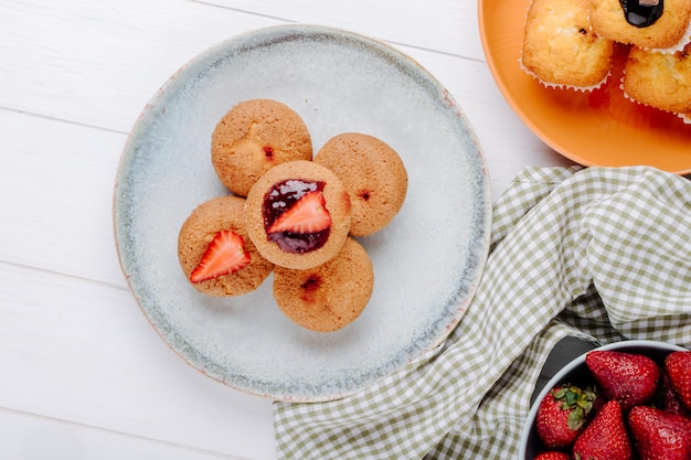 Bovenaanzicht muffins met aardbeien op een bord met aardbeien op een bord