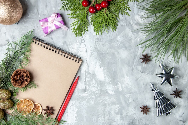 Bovenaanzicht notebook gedroogde schijfjes citroen anijs pijnboom takken rood potlood kerstboom speelgoed op grijze achtergrond vrije ruimte