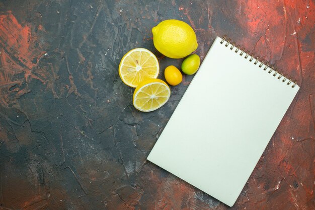 Bovenaanzicht notebook gesneden citroenen cumcuat op donkerrode grond kopie plaats