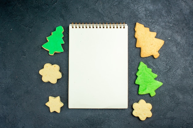 Bovenaanzicht notebook kerstkoekjes op donkere ondergrond