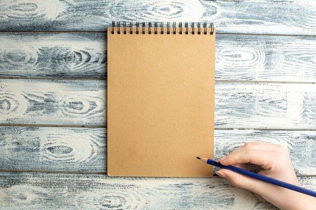 Bovenaanzicht notebook potlood in vrouwelijke hand op houten oppervlak