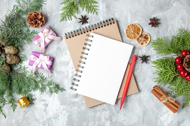 Bovenaanzicht notebooks kerstcadeaus dennenboom takken kaneelstokjes op grijze achtergrond