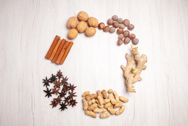 Bovenaanzicht noten en kaneelstokjes en verschillende soorten noten liggen in een cirkel op de witte tafel