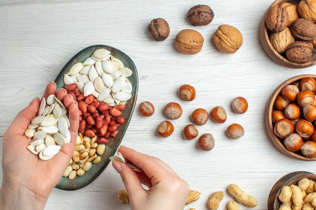 Bovenaanzicht notensamenstelling pinda's zaden hazelnoten en walnoten op witte tafel foto noot pistachenoten snack plant