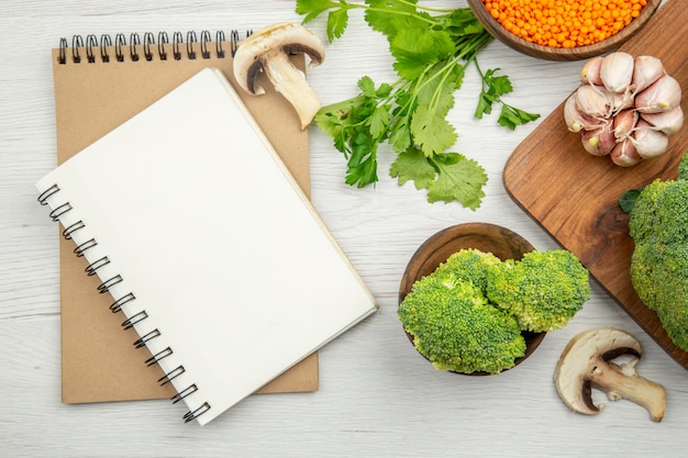 Bovenaanzicht notitieblokken knoflook broccoli op houten serveerplank