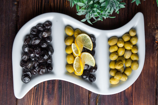Bovenaanzicht olijven olijven met citroen op een witte krullende plaat