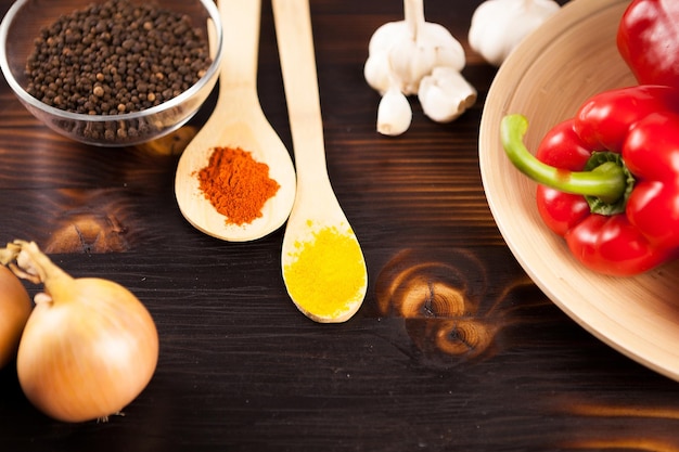 Bovenaanzicht op poederkruiden naast ui, paprika en knoflook op gebrande houten achtergrond