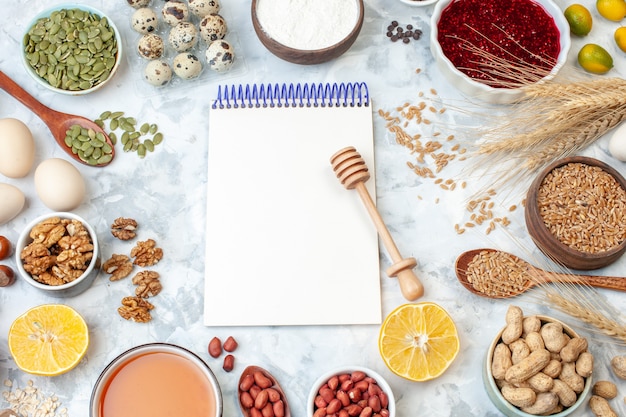 Bovenaanzicht open notitieblok met eieren meel gelei verschillende noten en zaden op witte noten kleur cake zoete taart foto suiker deeg