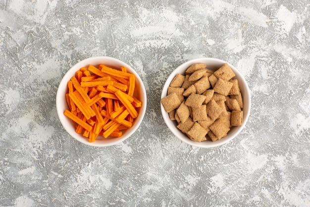 Bovenaanzicht oranje beschuit met kleine kussenkoekjes op wit bureau