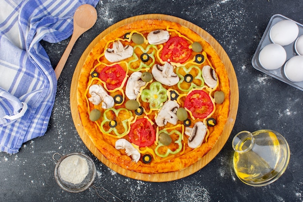 Bovenaanzicht paddestoel pizza met tomaten olijven champignons met bloem op het grijze bureau pizza deeg Italiaans eten