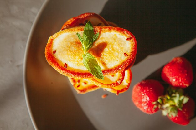 Bovenaanzicht pannenkoeken in plaat op elkaar met aardbeien op gestructureerde tafel. horizontaal