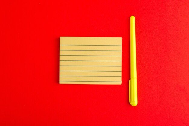 Bovenaanzicht papieren sticker met pen op rood oppervlak
