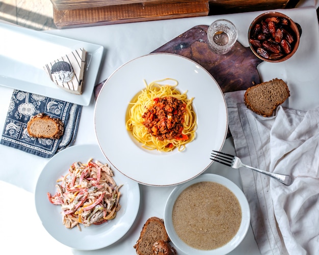 Bovenaanzicht pasta met verse salade en champignonsoep op het witte bureau