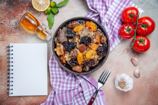 Bovenaanzicht pilaf pilaf op het tafellaken tomaten knoflook citroen olie vork wit notebook