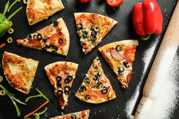Bovenaanzicht pizza mix met tomaten, olijven en paprika op zwarte tafel