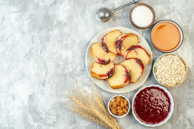 Bovenaanzicht plakjes jamcake op bord andere dingen in kommen op tafel met vrije ruimte