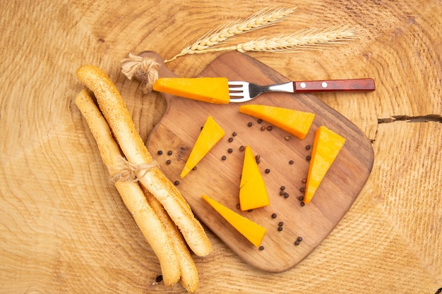Bovenaanzicht plakjes kaas en vork op snijplank tarwe spike wit brood op houten tafel
