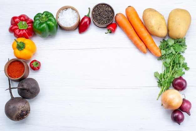 Bovenaanzicht plantaardige samenstelling met verse groenten greens rauwe bonen wortelen en aardappelen op de witte achtergrond maaltijd groente salade