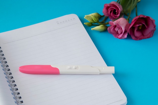Bovenaanzicht positieve zwangerschapstest en bloemen