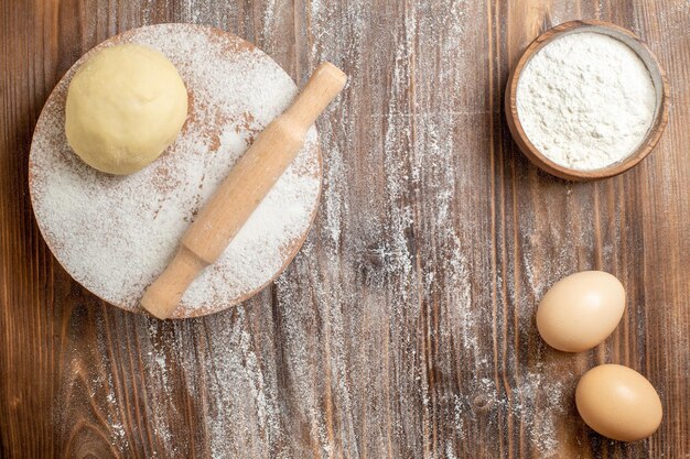 Bovenaanzicht rauw deegstuk met bloem op houten rustiek bureau maaltijdmeel bakdeeg