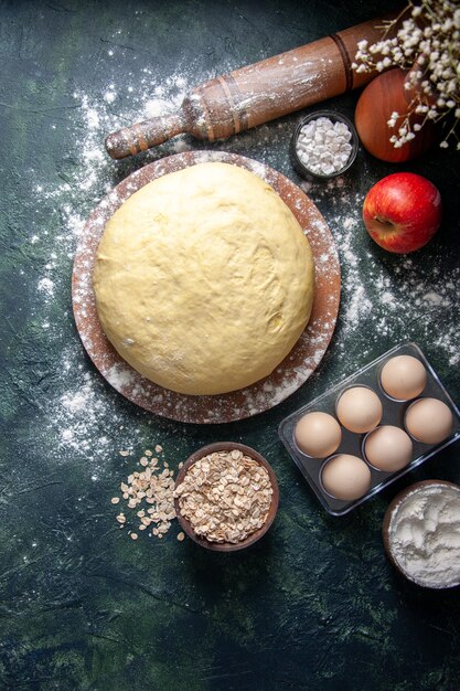 Bovenaanzicht rauw vers deeg met eieren op donkere achtergrond gebak bak cake rauwe hotcake taart vers ovendeeg