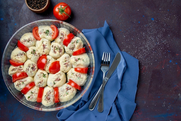 Bovenaanzicht rauwe deegstukken met gehakt en tomaten op de donkere maaltijd keukenschotel keuken foto kleur voedselsalade