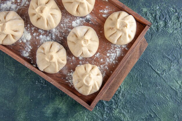 Bovenaanzicht rauwe dumplings met vlees binnen op donkere tafel maaltijd peper deeg vlees meel schotel koken