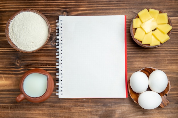 Bovenaanzicht rauwe eieren met melk en gesneden kaas op tafel maaltijd ontbijt deeg