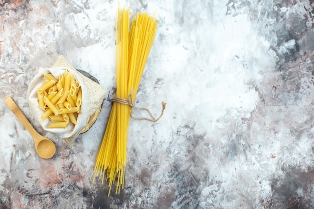 Bovenaanzicht rauwe gele pasta op lichte ondergrond
