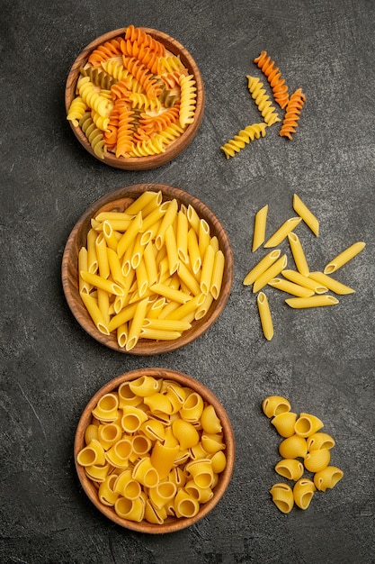 Bovenaanzicht rauwe italiaanse pasta anders gevormd binnen platen op grijs bureau