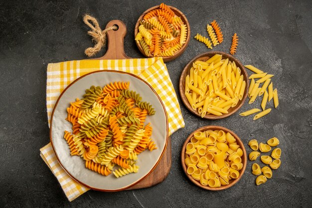 Bovenaanzicht rauwe Italiaanse pasta anders gevormd binnen platen op grijs