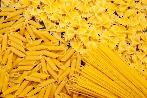 Bovenaanzicht rauwe Italiaanse pasta anders gevormd op de lichtgrijze achtergrond