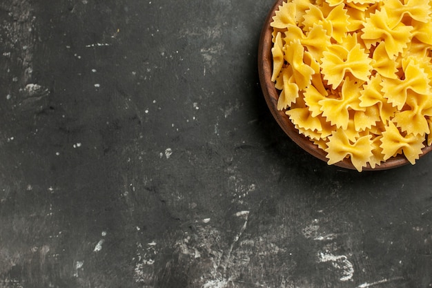 Bovenaanzicht rauwe Italiaanse pasta binnen plaat op donkergrijze achtergrond
