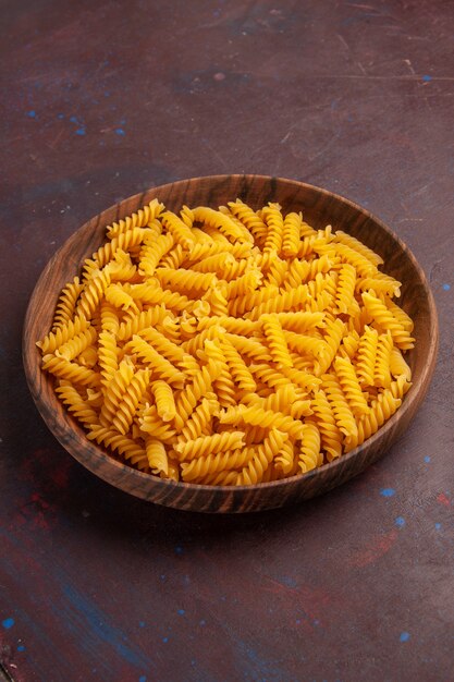 Bovenaanzicht rauwe italiaanse pasta in houten dienblad op het donkere bureau product pasta maaltijd voedsel groente