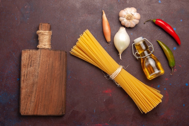 Bovenaanzicht rauwe italiaanse pasta lang gevormd op donkere paarse achtergrond maaltijd eten deeg pasta rauwe groente