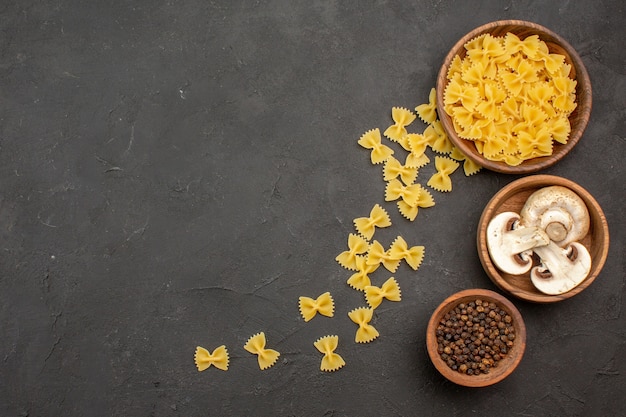 Bovenaanzicht rauwe Italiaanse pasta met champignons op donkere achtergrond