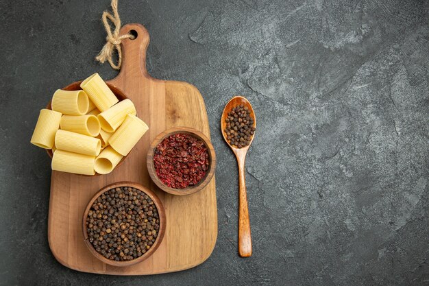 Bovenaanzicht rauwe italiaanse pasta met kruiden op de grijze achtergrond voedsel kruiden pasta deeg maaltijd pittig